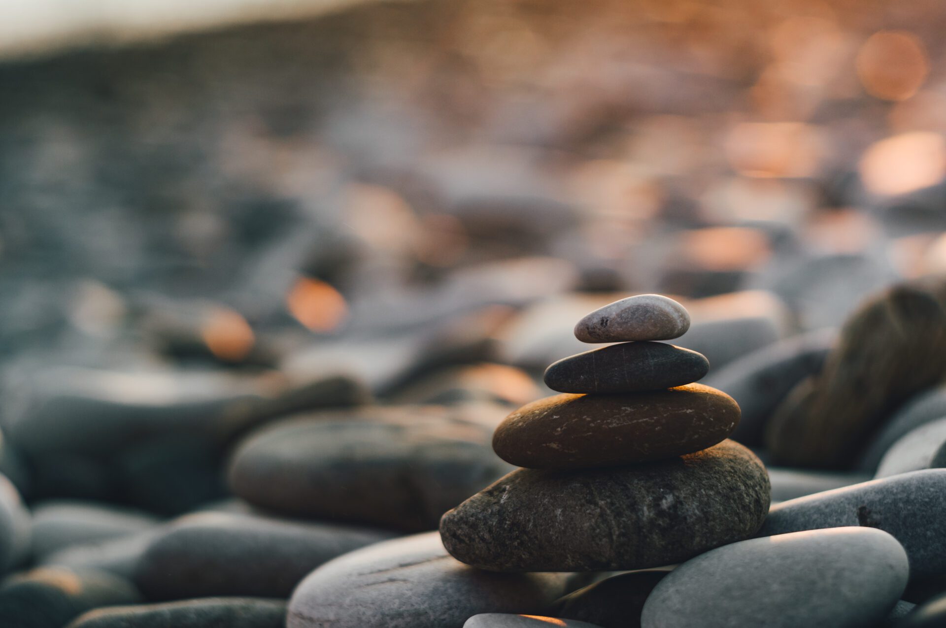 folded pyramid Zen pebble stones on the sea beach at sunset